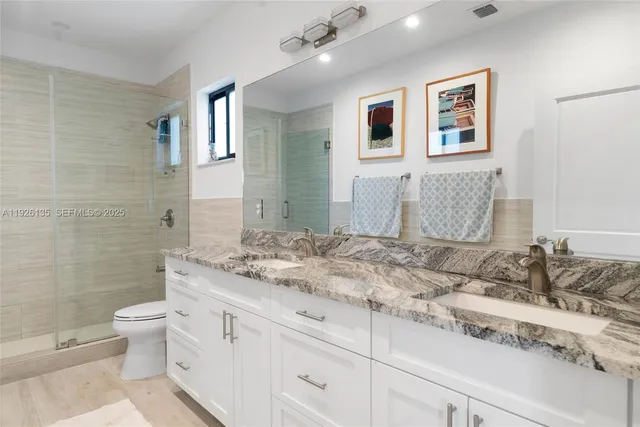 a bathroom with a granite countertop sink mirror and toilet
