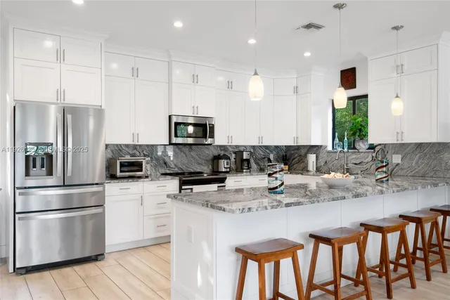 a kitchen with stainless steel appliances granite countertop a white cabinets and a refrigerator