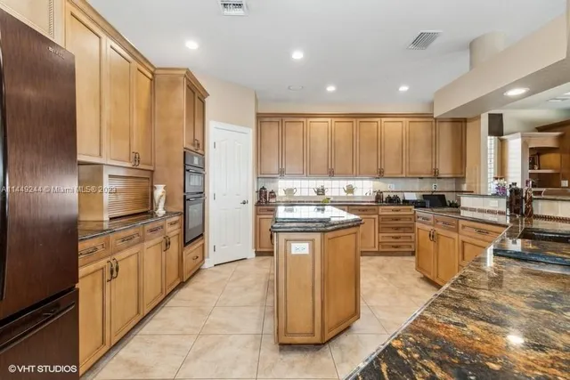 a kitchen with stainless steel appliances granite countertop a stove top oven a sink and a refrigerator