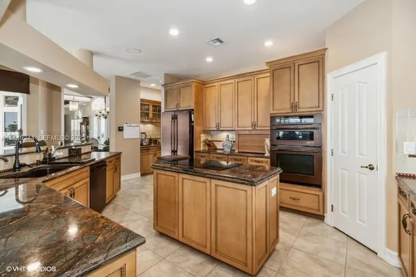 a kitchen with stainless steel appliances granite countertop a stove top oven a sink and a refrigerator