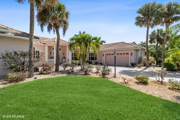 a view of a house with a yard and palm trees