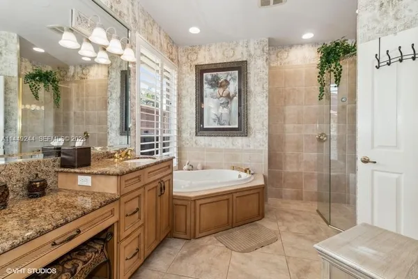 a bathroom with a granite countertop sink a mirror a bathtub and shower