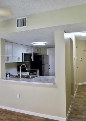 a view of kitchen with stainless steel appliances granite countertop a sink and a refrigerator