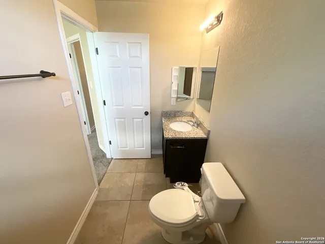a bathroom with a granite countertop toilet and a sink