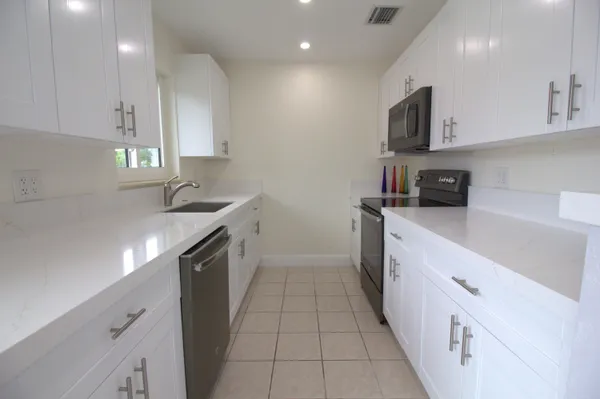 a kitchen with stainless steel appliances granite countertop a sink a stove and a refrigerator