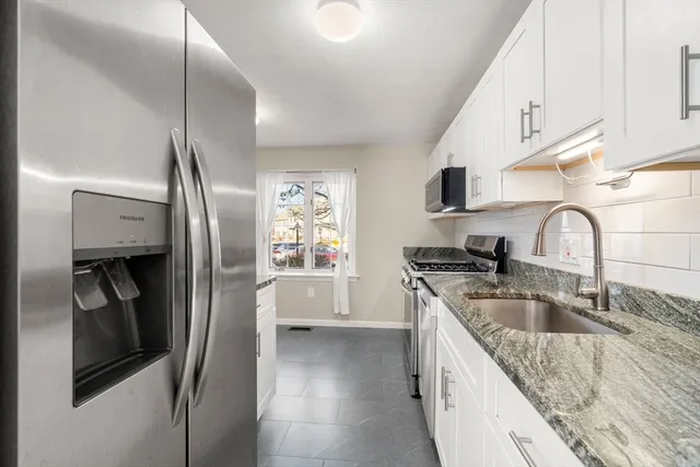 a kitchen with granite countertop white cabinets and stainless steel appliances