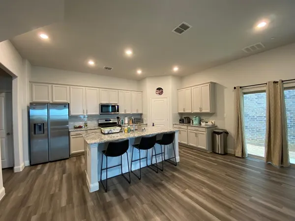 a kitchen with kitchen island granite countertop a sink cabinets and stainless steel appliances