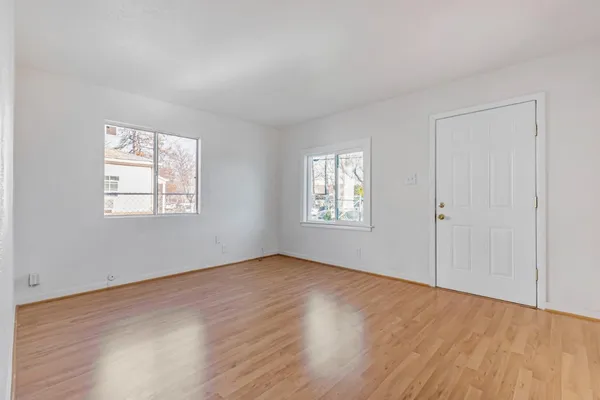 an empty room with wooden floor and windows