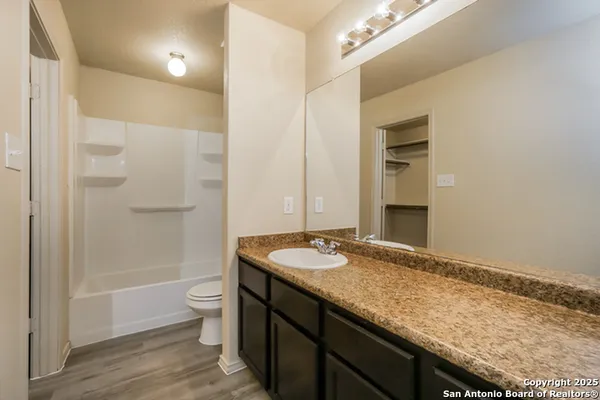 a bathroom with a granite countertop sink a toilet a mirror and shower
