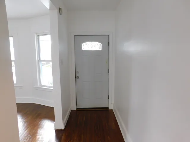 a view of hallway with window and wooden floor