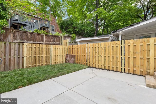 a view of a black gate with wooden fence