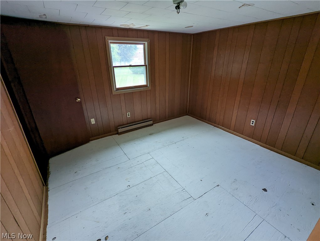 308 Thomas Road Lisbon, OH 44432 - Photo 10 of 13 Spare room featuring wood walls and a baseboard radiator