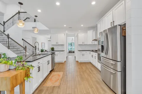 a kitchen with stainless steel appliances granite countertop a refrigerator and white cabinets