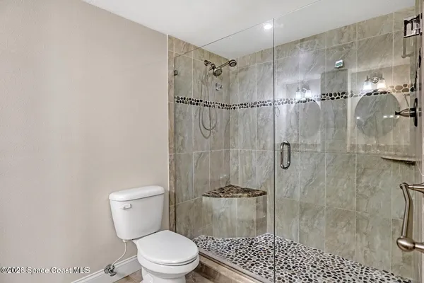 a bathroom with a granite countertop sink a toilet and mirror