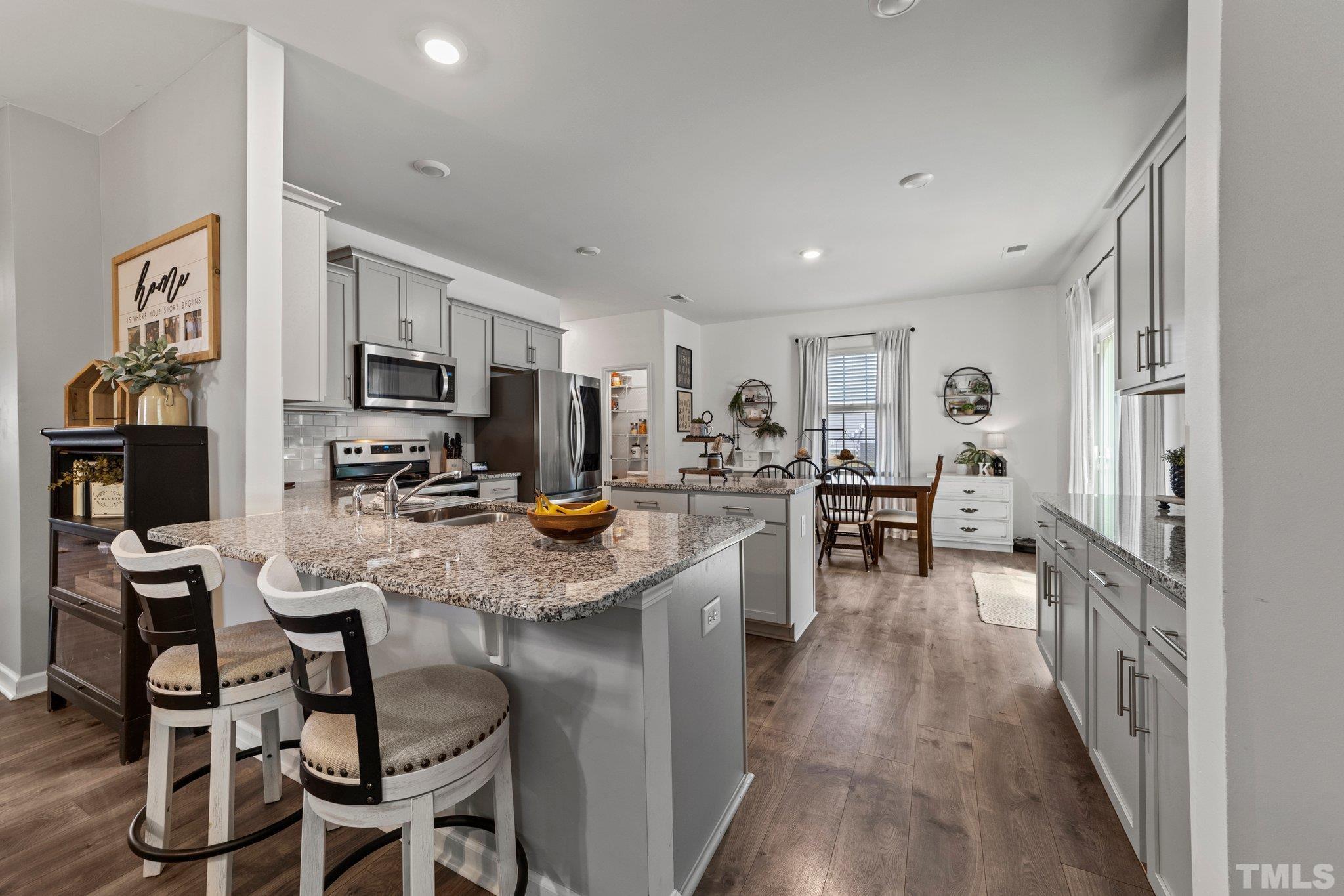 3116 Longpine Road Burlington, NC 27215 - Photo 10 of 29 a kitchen with stainless steel appliances kitchen island granite countertop a refrigerator a stove a sink a dining table and chairs with wooden floor