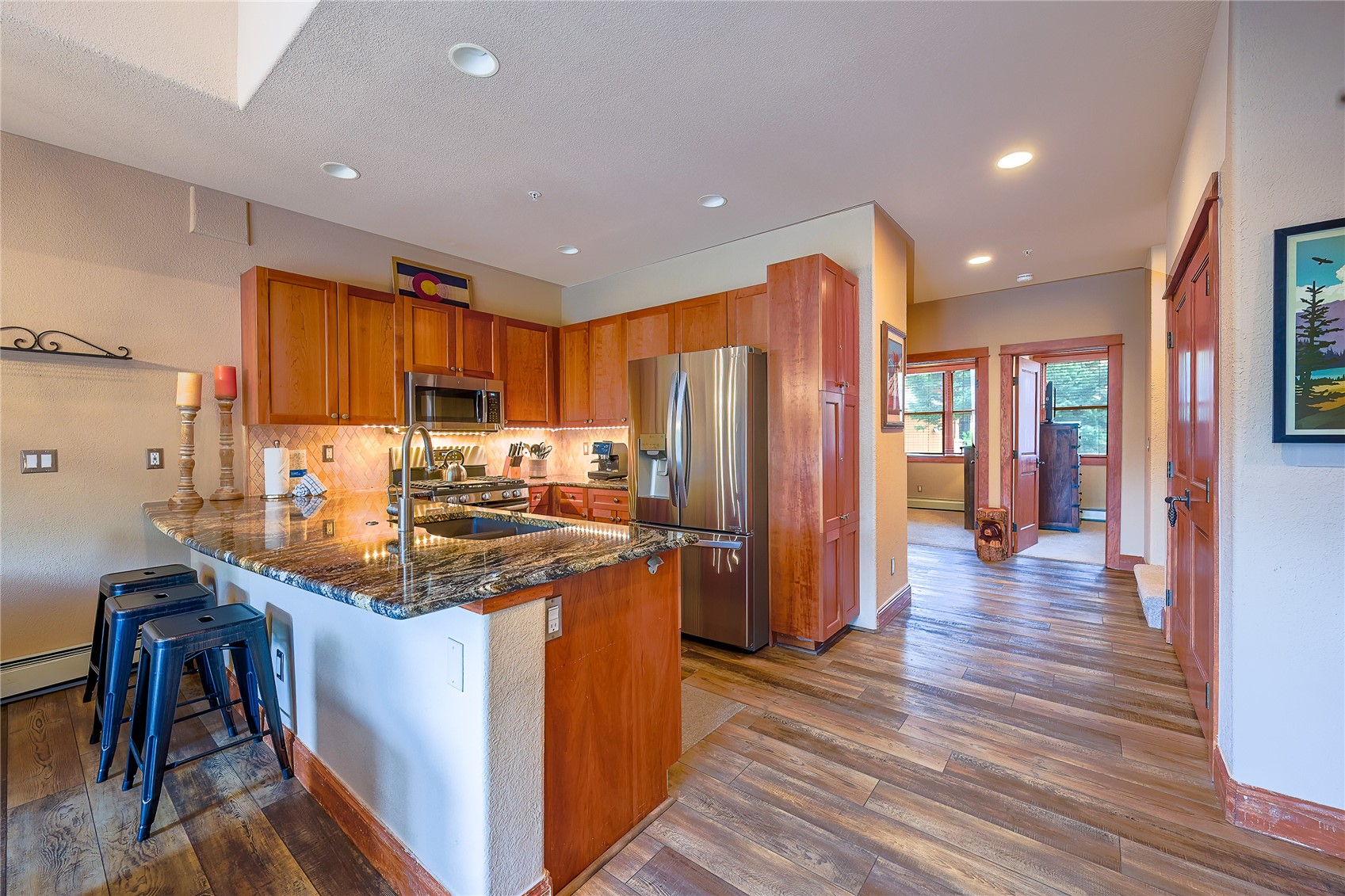 63 Antlers Gulch Road, Unit 104 Keystone, CO 80435 - Photo 5 of 23 Kitchen featuring stainless steel appliances, wood-type flooring, dark stone counters, and kitchen peninsula