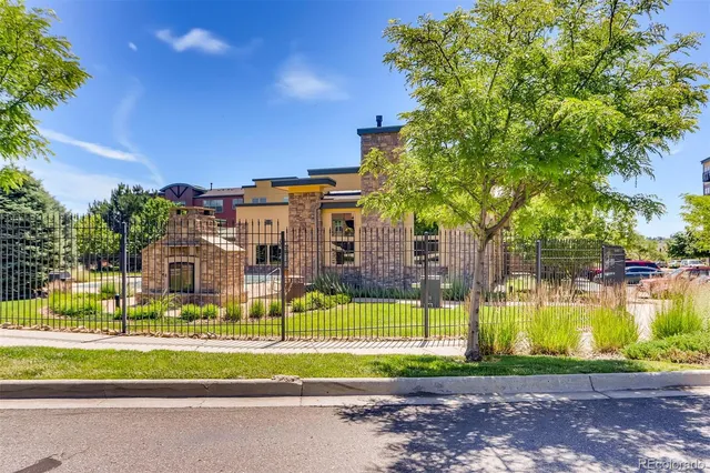 a view of a big building in front of a big yard and large trees