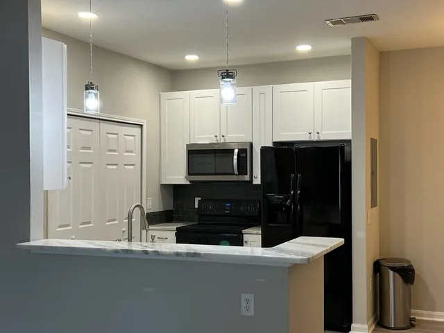 a kitchen with granite countertop a refrigerator and a sink