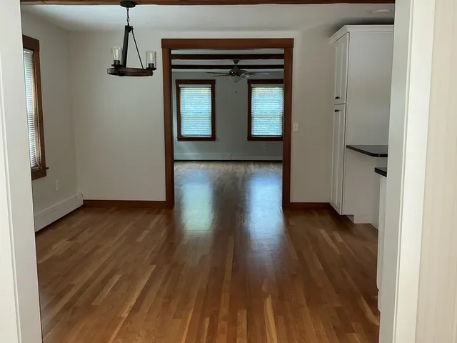 a view of a hallway with wooden floor and a cabinet
