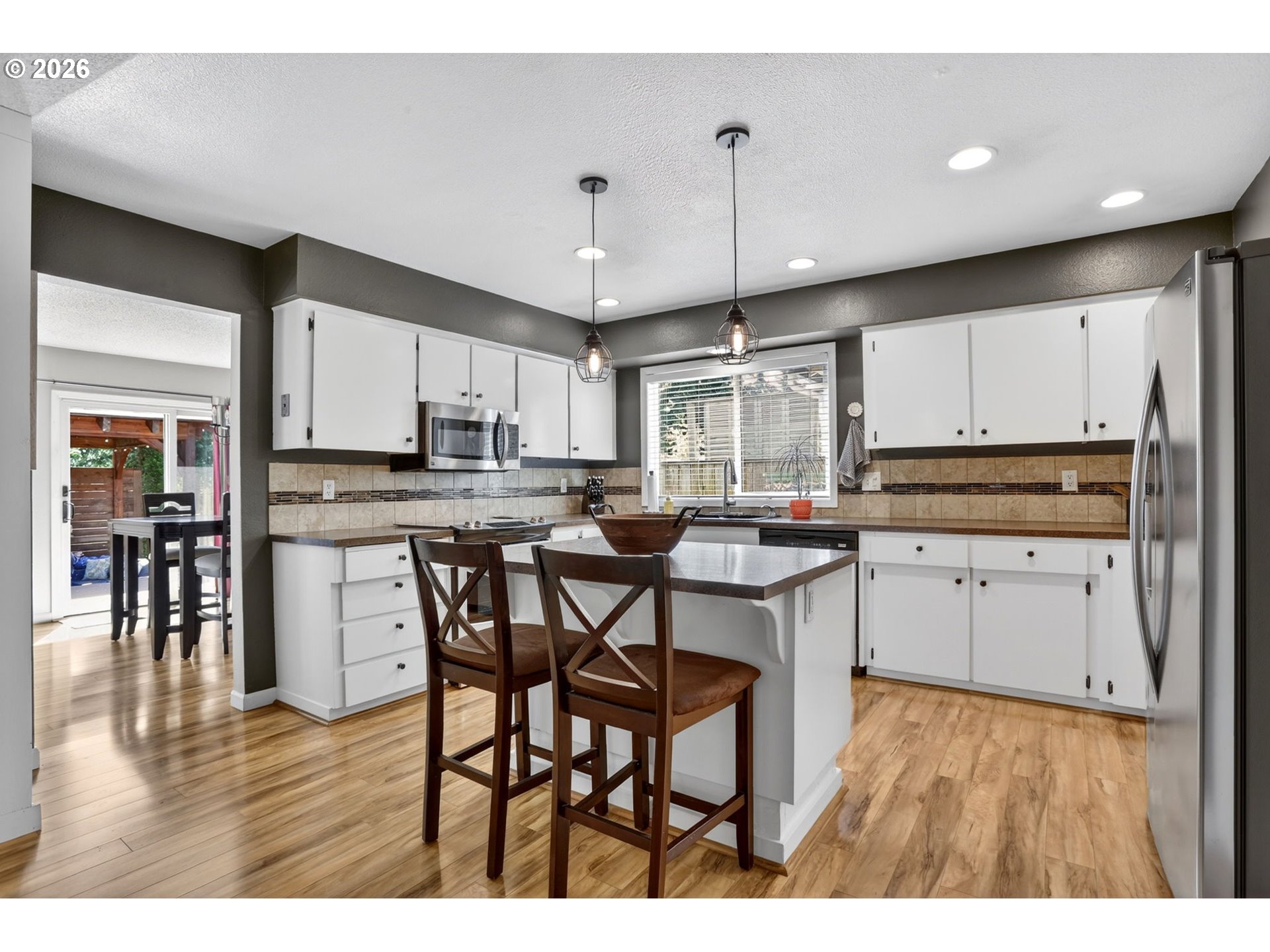 1776 Southeast 114th Place Portland, OR 97216 - Photo 15 of 47 a kitchen with stainless steel appliances kitchen island granite countertop a table chairs refrigerator and microwave