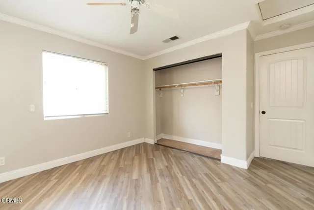 an empty room with wooden floor closet and windows