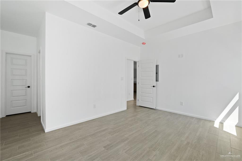 3208 Briggs Street, Unit 1 Weslaco, TX 78596 - Photo 3 of 12 Spare room with a raised ceiling, light wood-type flooring, ceiling fan, and visible vents