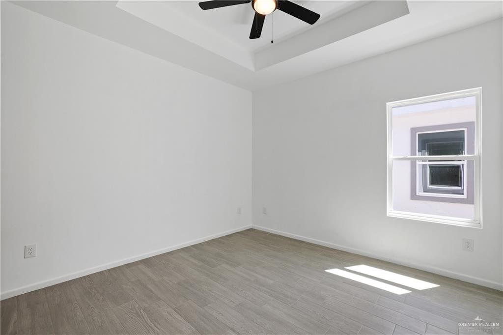 3208 Briggs Street, Unit 1 Weslaco, TX 78596 - Photo 6 of 12 Unfurnished room with a raised ceiling, wood finished floors, ceiling fan, and baseboards