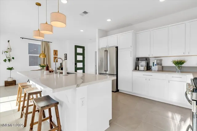 a kitchen with stainless steel appliances a refrigerator a sink a stove a dining table and chairs with wooden floor