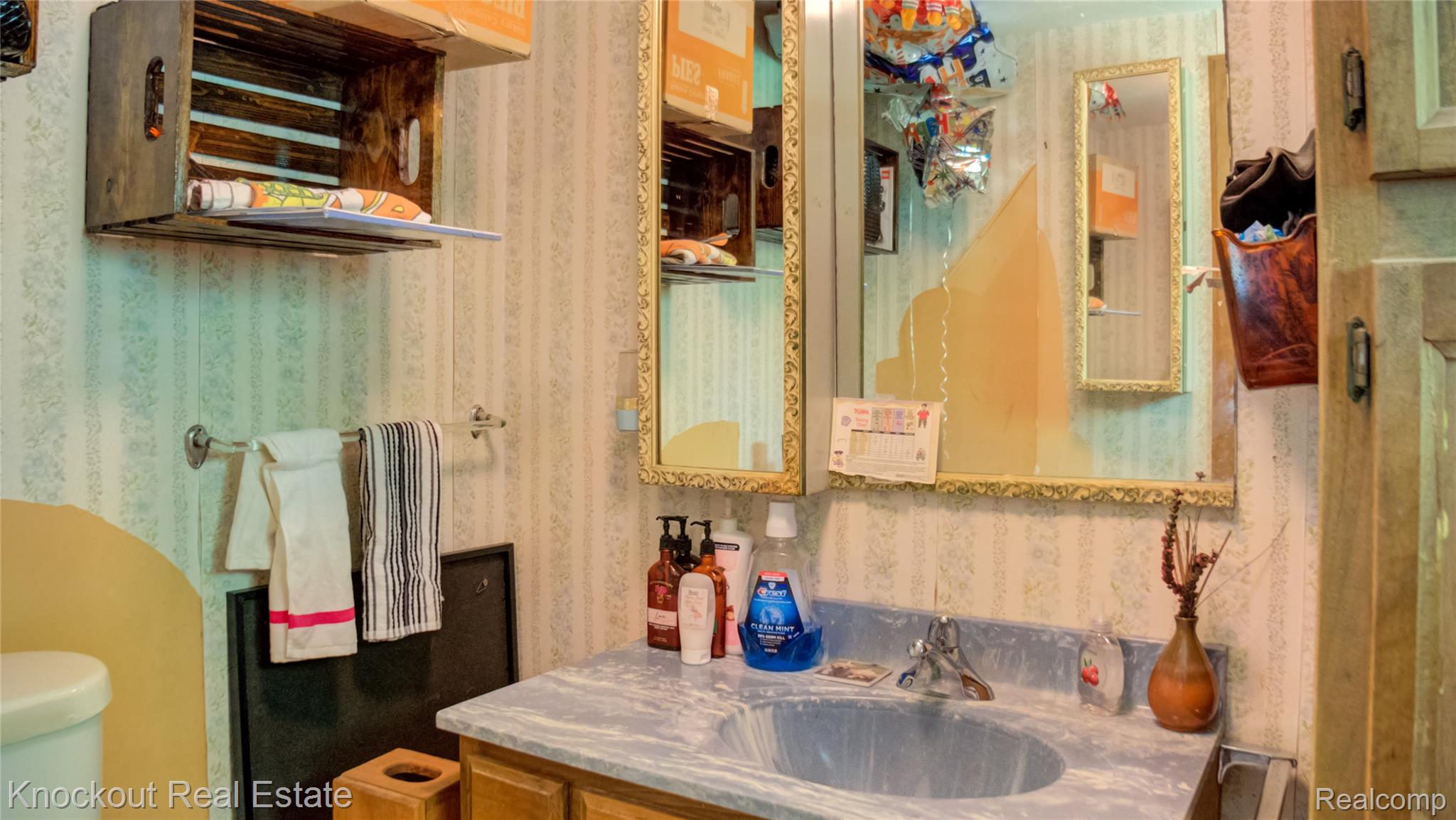 4195 Williamson Road Saginaw, MI 48601 - Photo 22 of 50 Bathroom vanity featuring an integrated sink with a single-handle faucet, a framed wall mirror, and wallpapered walls