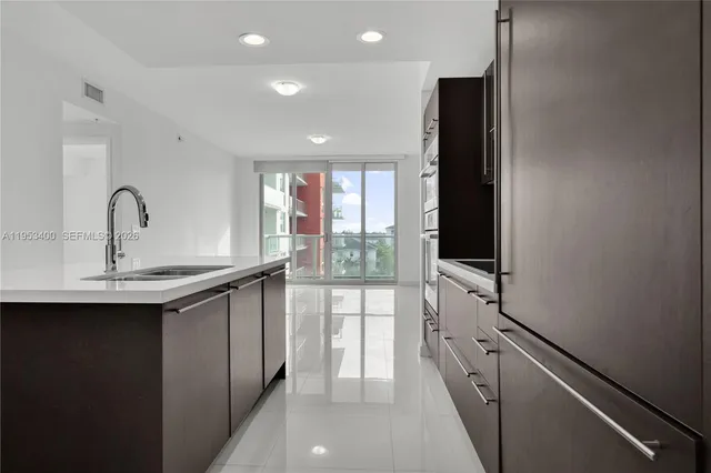 a kitchen with stainless steel appliances kitchen island granite countertop a refrigerator and a sink