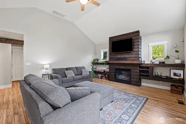 a living room with furniture a fireplace a flat screen tv and kitchen view