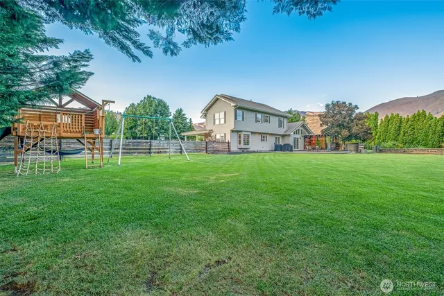 a view of a house with a big yard and large trees