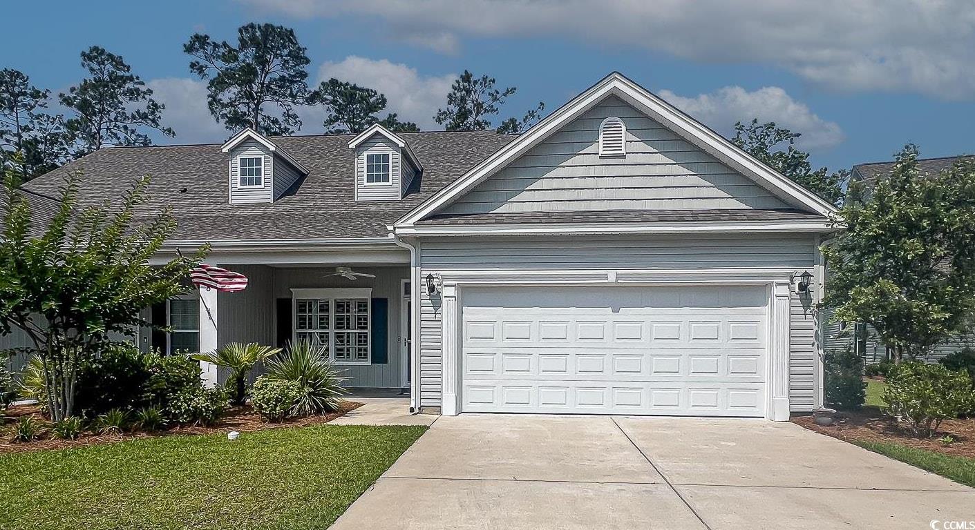View of front of house with a front yard, driveway, an attached garage, and a shingled roof