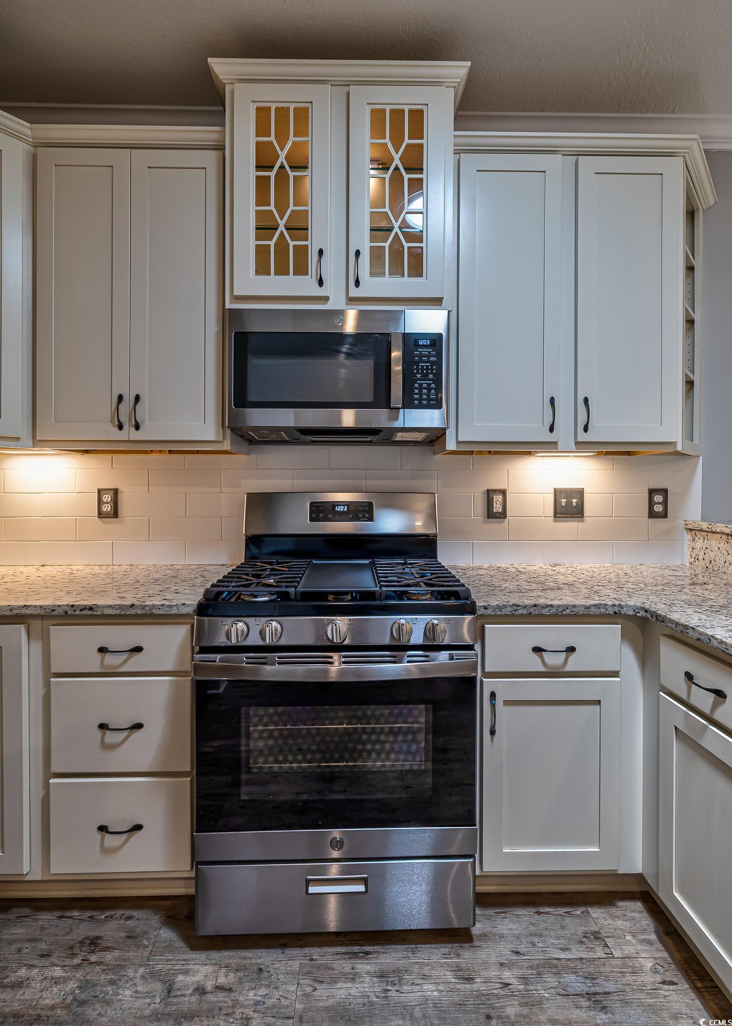 648 Sunnyside Drive, Unit 102 Murrells Inlet, SC 29576 - Photo 15 of 21 Kitchen featuring appliances with stainless steel finishes, backsplash, dark wood-style flooring, and light stone counters