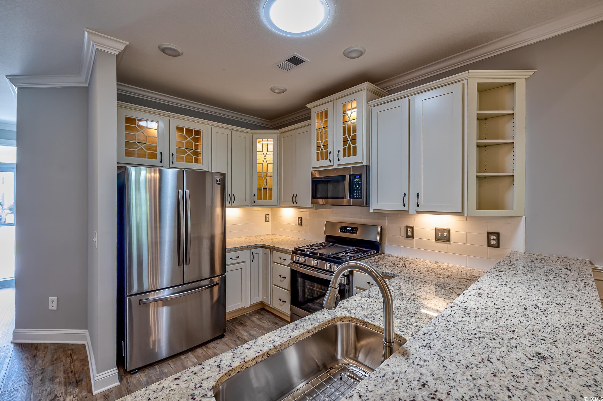 648 Sunnyside Drive, Unit 102 Murrells Inlet, SC 29576 - Photo 16 of 21 Kitchen with stainless steel appliances, a sink, light stone countertops, crown molding, and dark wood-type flooring