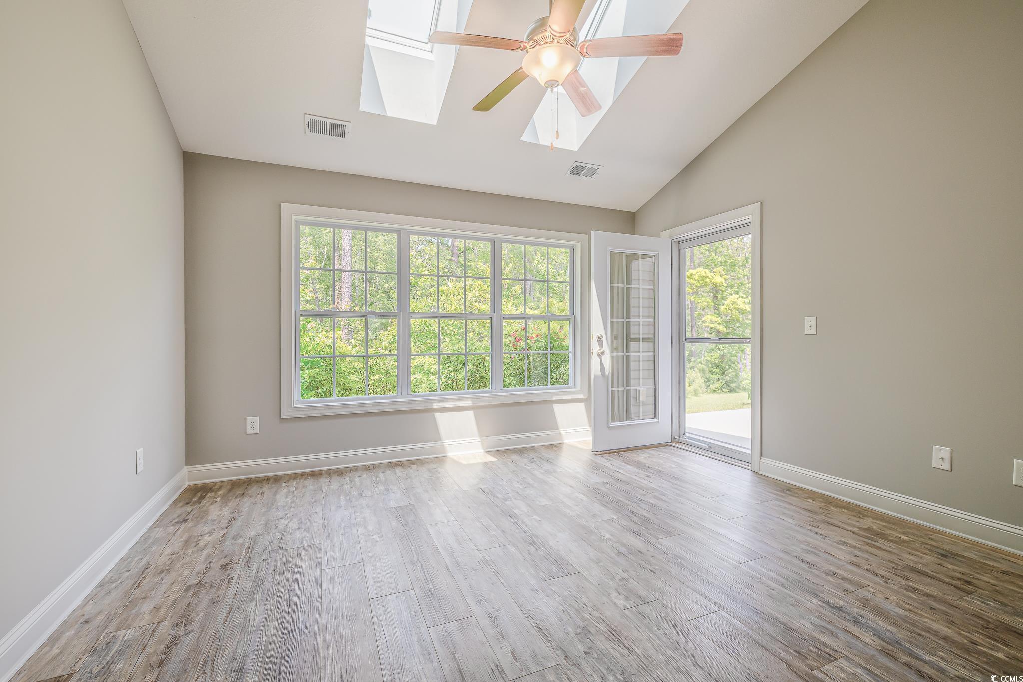 648 Sunnyside Drive, Unit 102 Murrells Inlet, SC 29576 - Photo 4 of 21 Empty room featuring a skylight, ceiling fan, wood finished floors, baseboards, and high vaulted ceiling