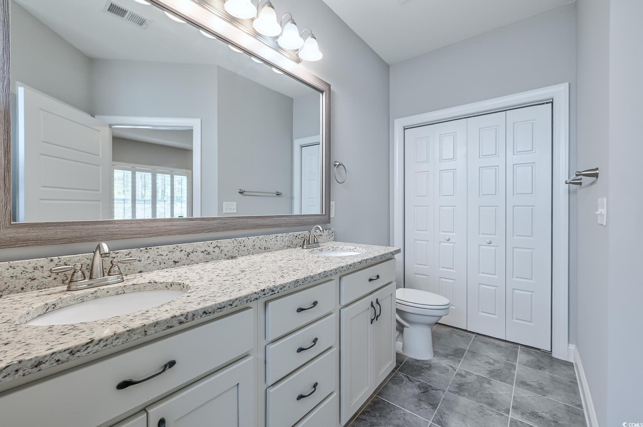 648 Sunnyside Drive, Unit 102 Murrells Inlet, SC 29576 - Photo 9 of 21 Full bathroom with double vanity, a closet, toilet, and baseboards