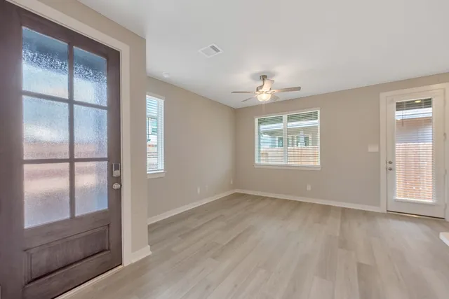 an empty room with wooden floor chandelier and windows