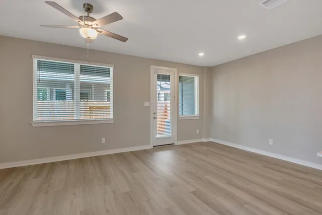 a view of empty room with wooden floor and fan