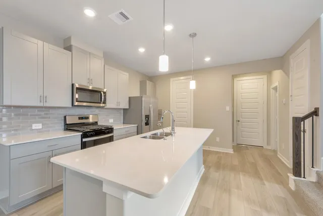 a kitchen with stainless steel appliances kitchen island granite countertop a sink a stove a refrigerator and cabinets