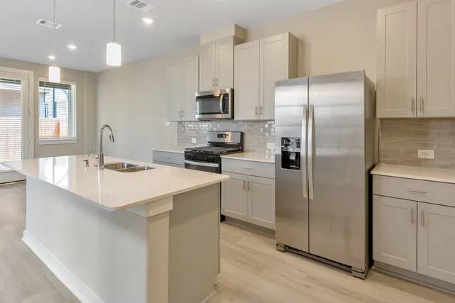 a kitchen with kitchen island stainless steel appliances a sink cabinets and refrigerator