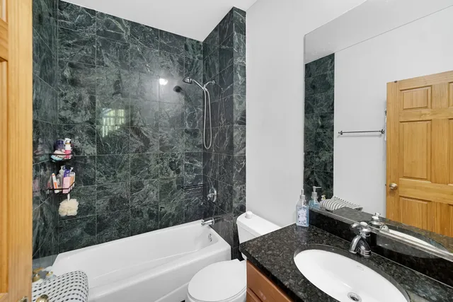 a bathroom with a granite countertop sink toilet and shower