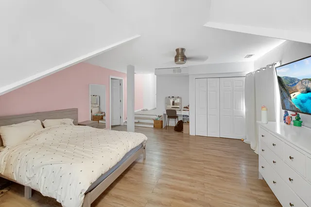 a spacious bedroom with a bed and a flat screen tv