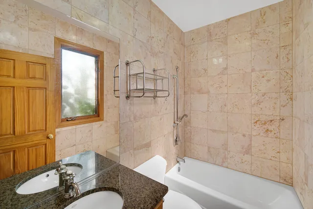 a bathroom with a granite countertop sink mirror toilet and bathtub