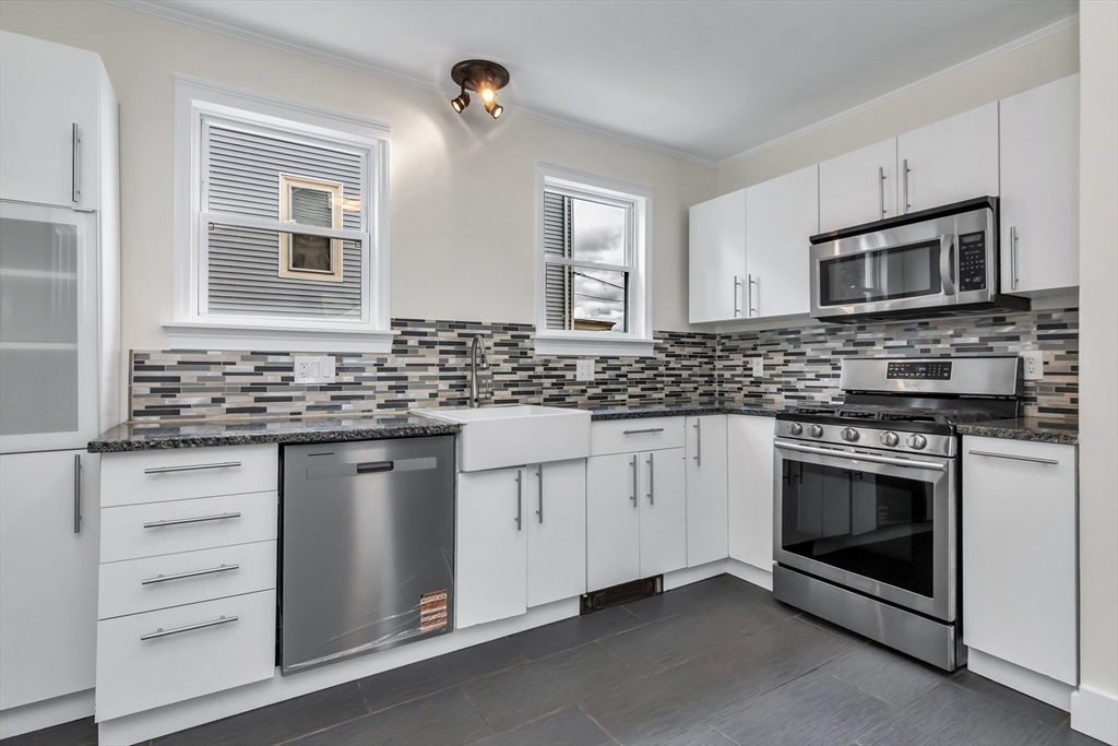 6 Dexter Street Haverhill, MA 01830 - Photo 17 of 42 a kitchen with stainless steel appliances granite countertop white cabinets a stove a sink and a microwave