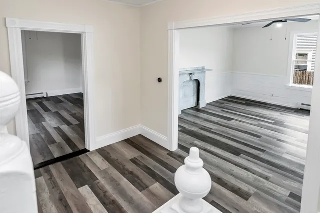 a view of an empty room with a window and wooden floor