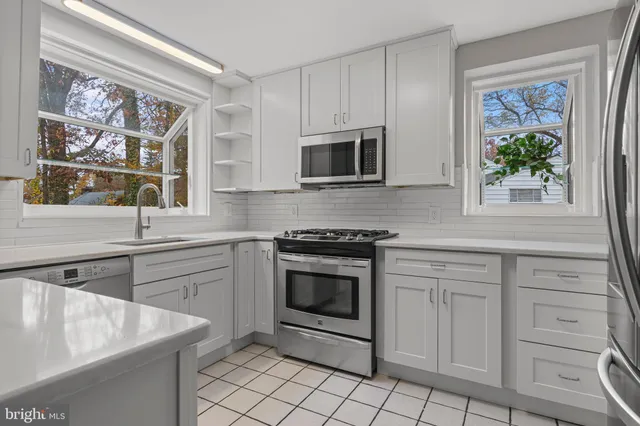 a kitchen with white cabinets stainless steel appliances and a window
