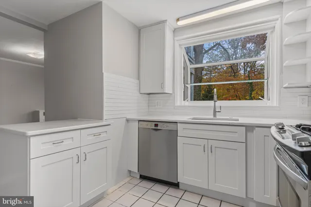 a kitchen with white cabinets and a window