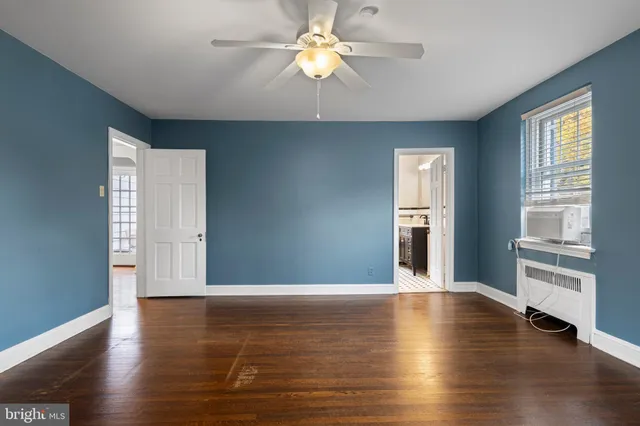 a view of an empty room with window and wooden floor
