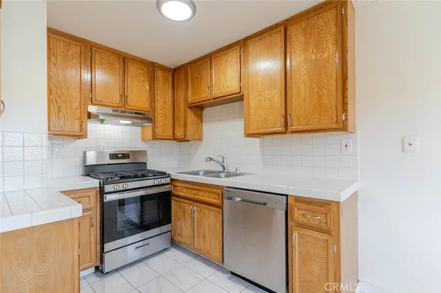 a kitchen with stainless steel appliances granite countertop wooden cabinets stove top oven and sink